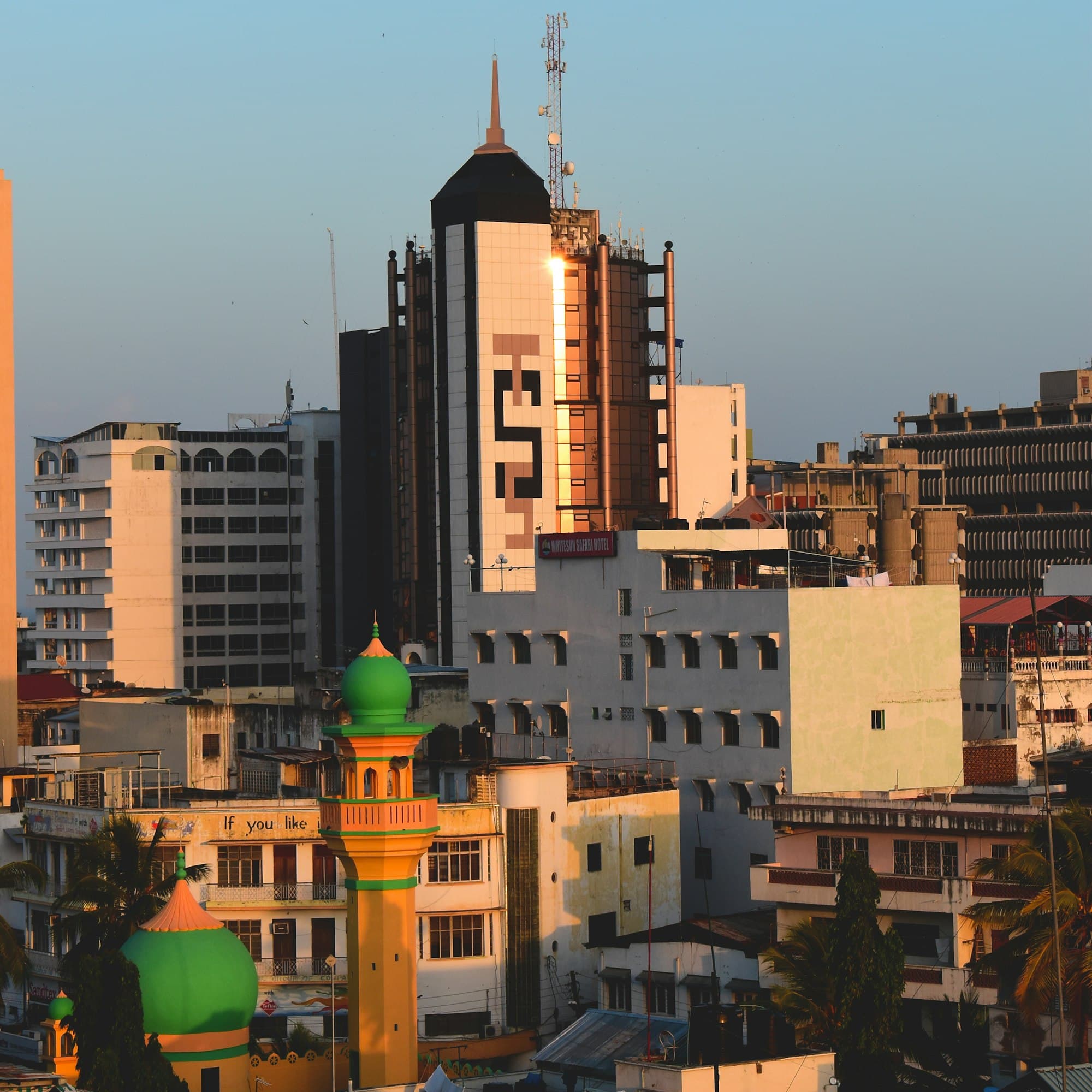 Mombasa town centre at golden hour, with office buildings and a green-domed mosque minaret