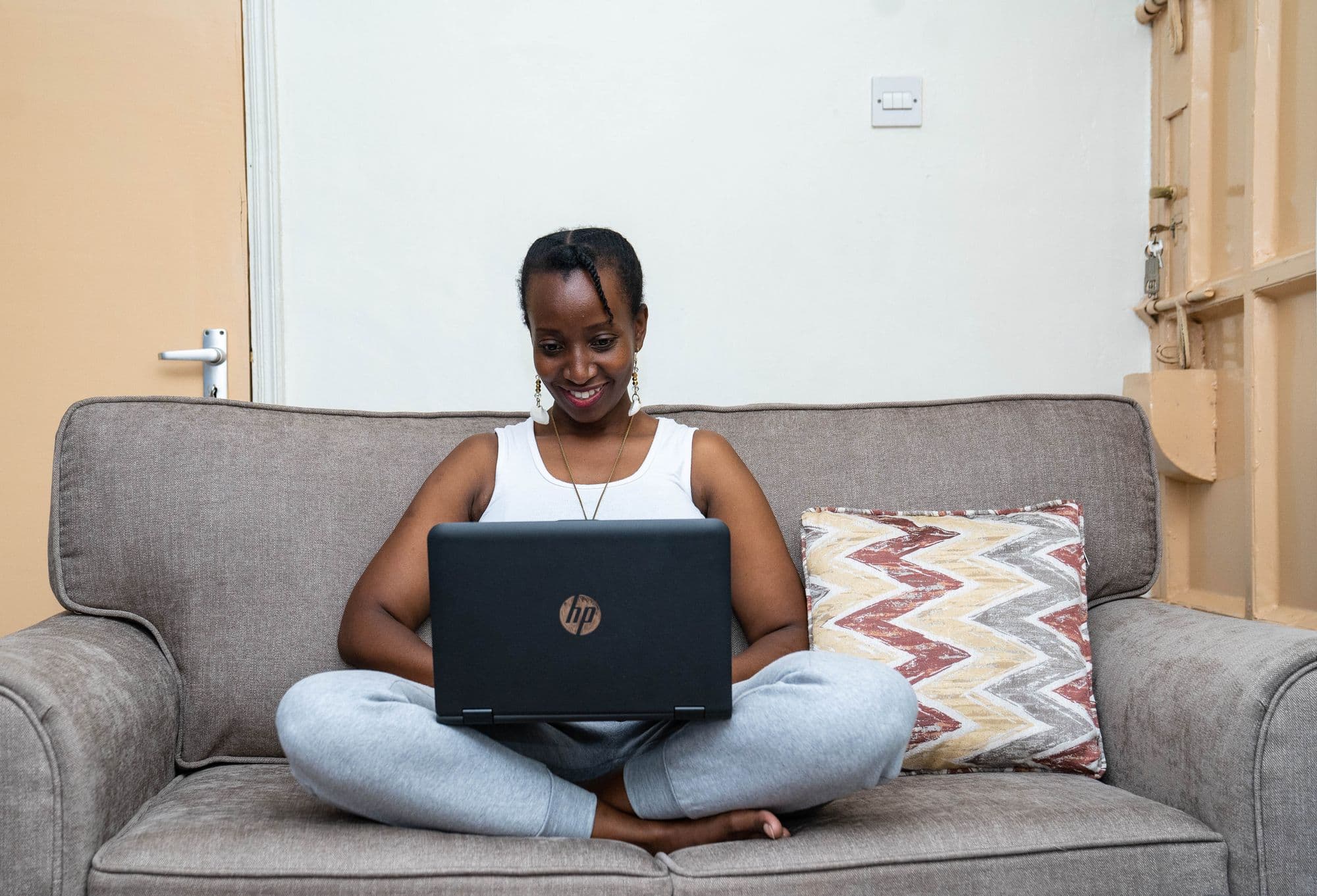 Smiling young woman sitting cross-legged on a sofa using a laptop