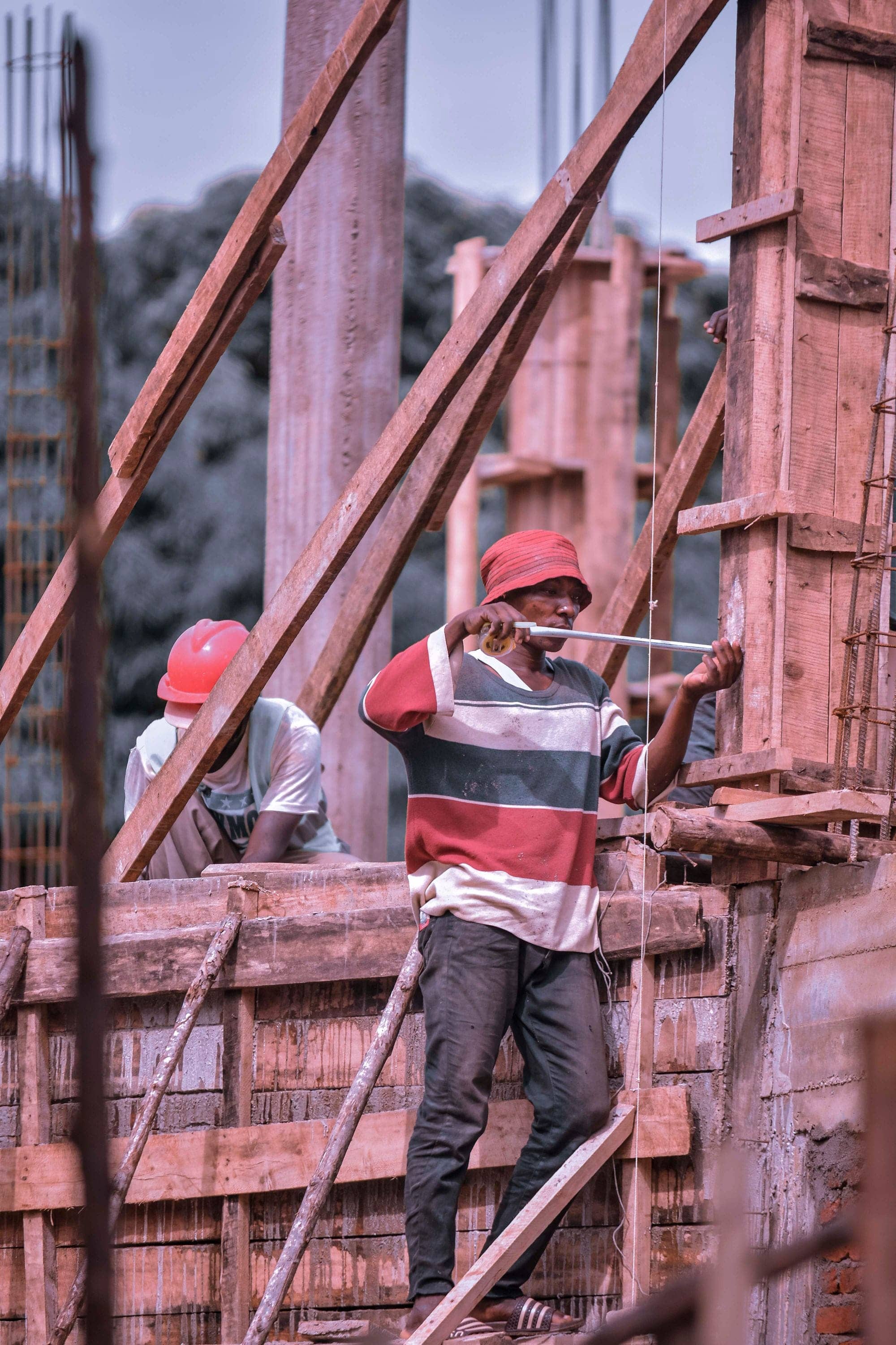 Construction workers in hard hats assembling timber formwork for concrete columns
