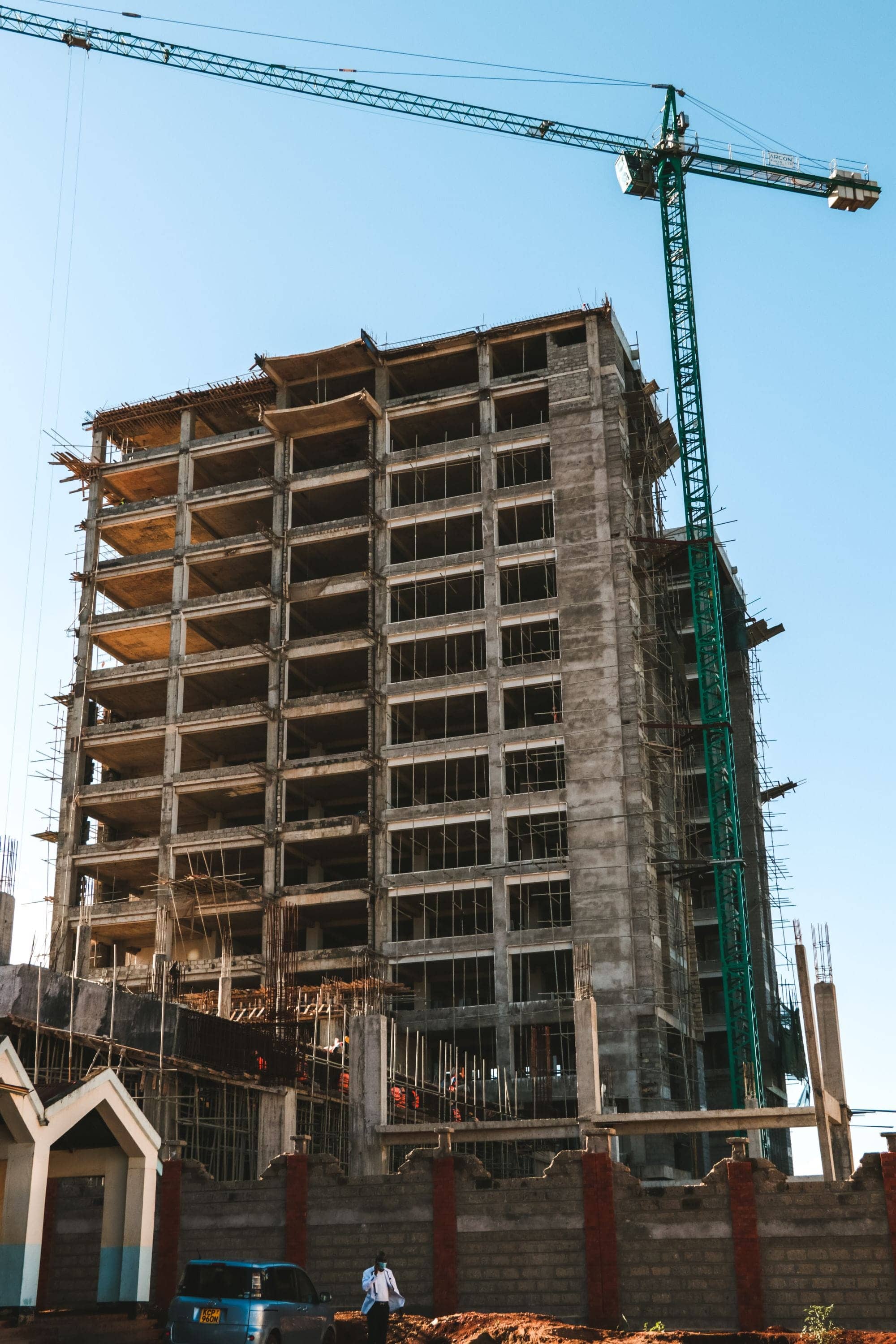 Multi-storey concrete building frame under construction beside a tower crane